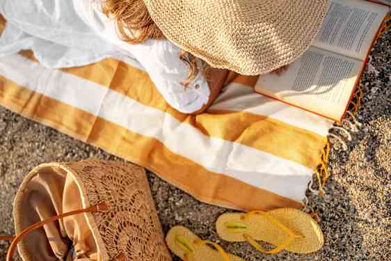 Kvinde læser bog på stranden
