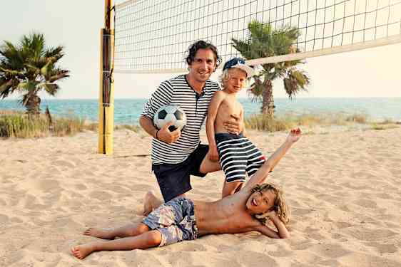 Familie spiller volleyball på stranden