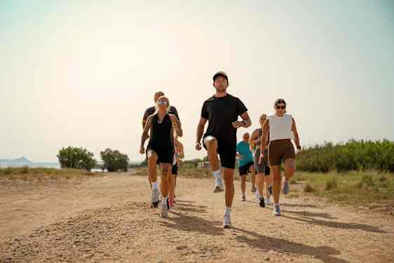 En gruppe mennesker som jogger mot kamera på en grusvei