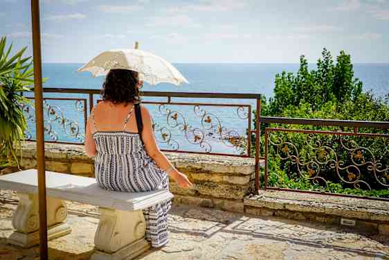 Kvinne under parasoll skuer ut over vannet