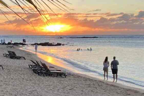 Par går på en strand i solnedgang på Mauritius