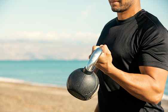 Nærbilde av en mann i mørk tskjorte som løfter en vekt