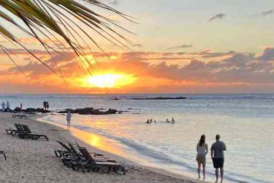 Par går på en strand i solnedgang på Mauritius