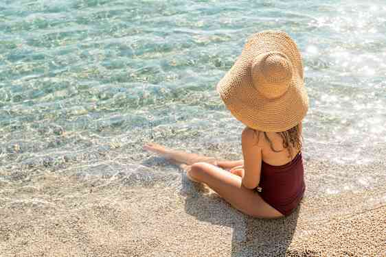 Kvinne sitter ved vannet