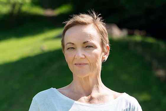 Portrett av Ellen Johannesen i hvit tskjorte og frodig bakgrunn
