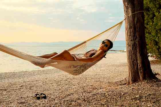 Kvinne i hengekøye på en idyllisk hvit sandstrand 