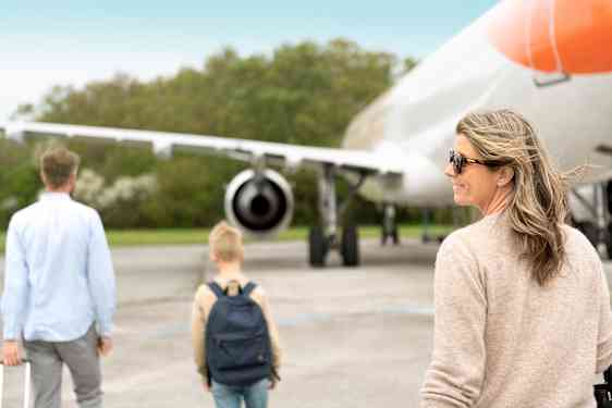 To voksne og ett barn på vei mot et fly