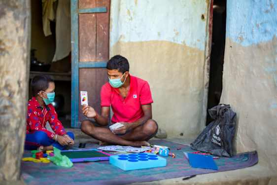 Voksen mann, fra Redd Barna, spiller kortspill med en ung gutt.