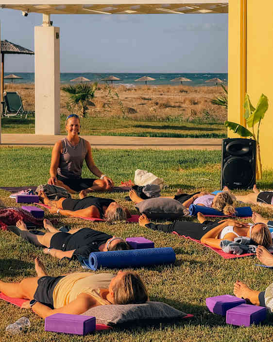 En gruppe mennesker gjør yoga på et gressområde.