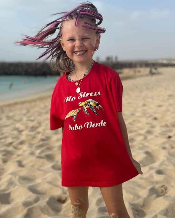 Glad og fornøyd jente iført "no stress" t-skjorte på stranden