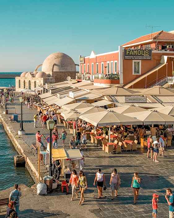 Livlig havneområde med restauranter, uteserveringer og utsikt mot havet