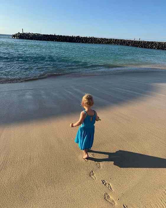 Jente går på stranden, kun hennes fotspor å se