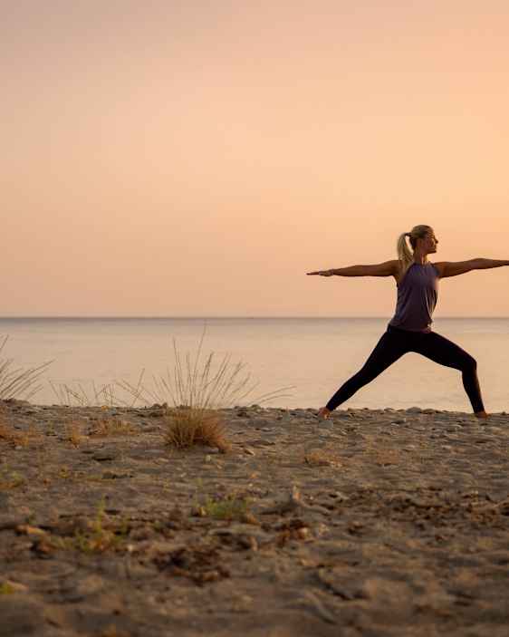 Kvinna yogar på en strand
