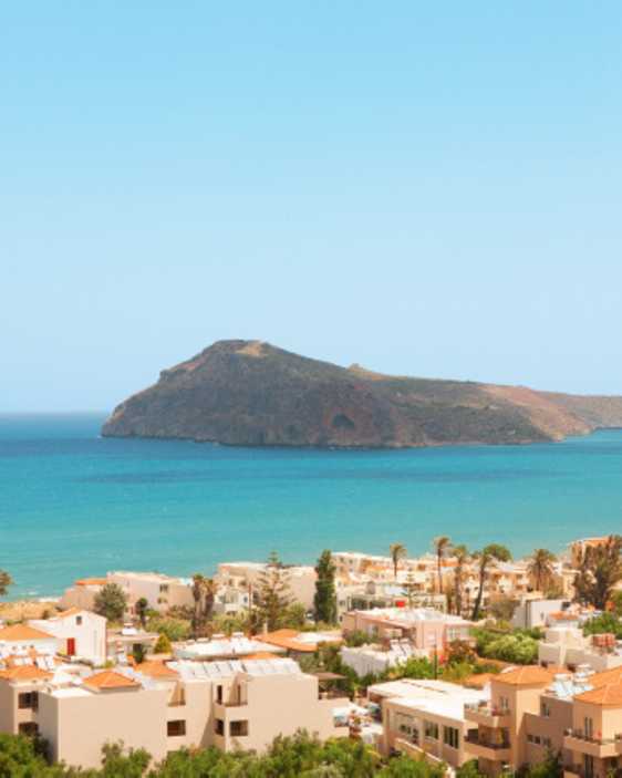 Utsikt over Platanias med turkist hav og en liten øy i bakgrunnen.