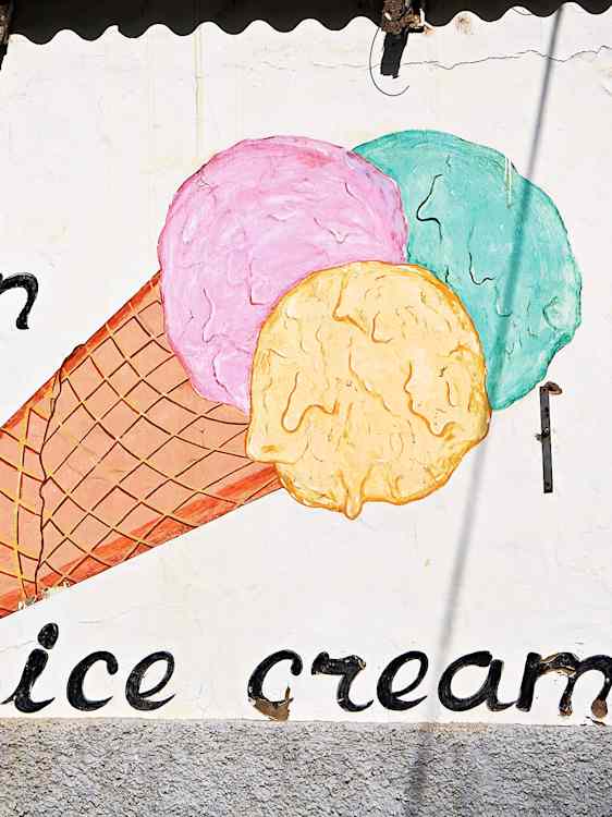 En lys vegg har en illustrasjon av en iskremkjeks med flere fargede kuler. Under står teksten "ice cream" i svart.