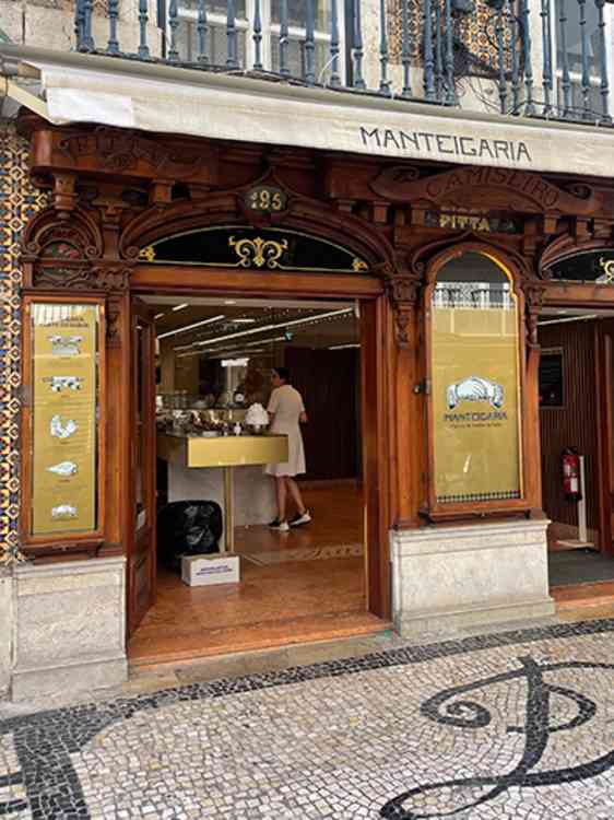 Inngangen til bakeriet Manteigaria har en rikt utsmykket trefasade med store vinduer og åpne dører. Inne i lokalet er disken og bakeriet synlig fra gaten.