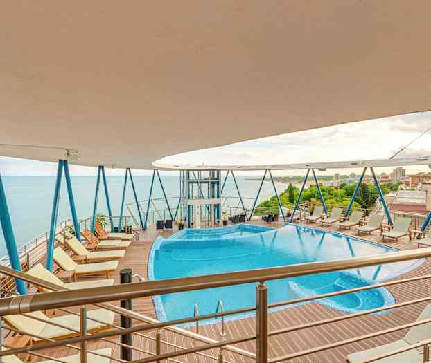 Utendørs basseng med boblebad på høyt dekk med havutsikt. (AI-generert tekst)