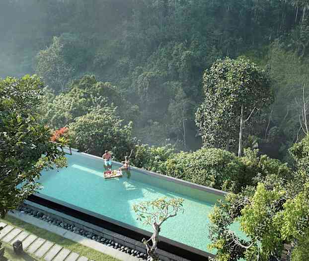 Et infinitybasseng med utsikt over en frodig skog. To personer i bassenget med en frokostbrett. (AI-generert tekst)