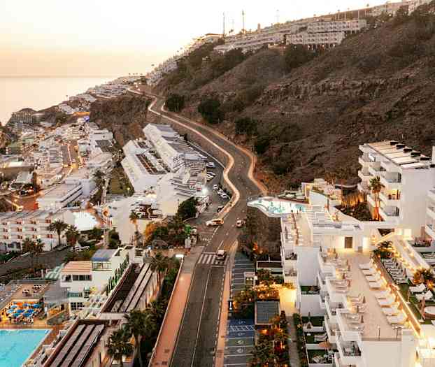 Utsikt over hoteller og skråning ved kysten, med havet i bakgrunnen. (AI-generert tekst)