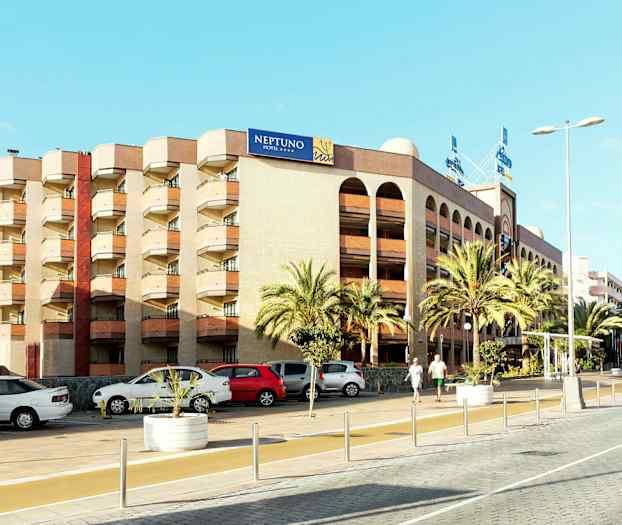 En flerfarget bygning med et skilt med teksten "NEPTUNO HOTEL", omgitt av palmer og parkerte biler. (AI-generert tekst)