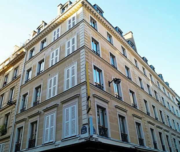 Et hjørnebygg med flere etasjer og skodder. (AI-generert tekst)