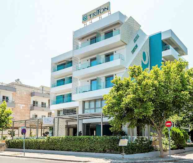 En moderne hotellbygning med fem etasjer og balkonger, omgitt av trær. (AI-generert tekst)