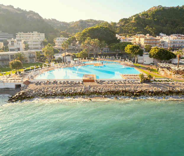 Et stort basseng ved havet, omgitt av bygninger og grøntområder. (AI-generert tekst)