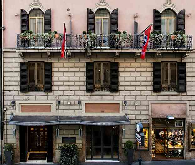 Bygningen har en klassisk fasade med balkonger og blomsterkasser. (AI-generert tekst)