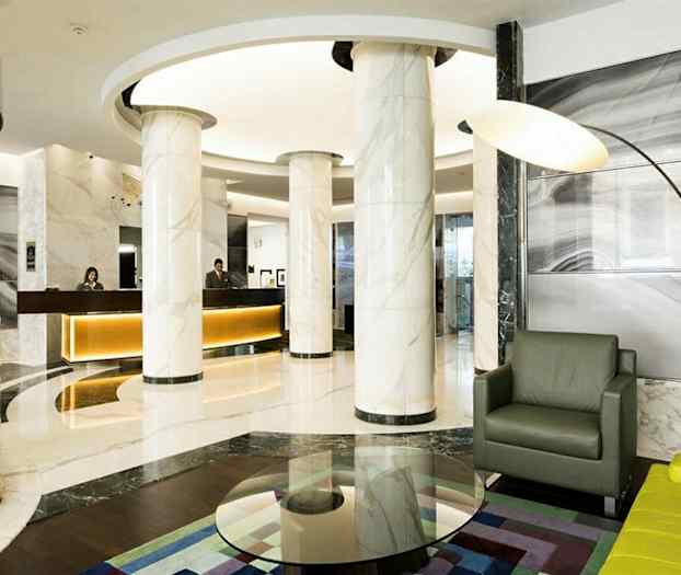 Moderne hotellobby med marmorsøyler, resepsjonsdisk og sittegruppe. (AI-generert tekst)