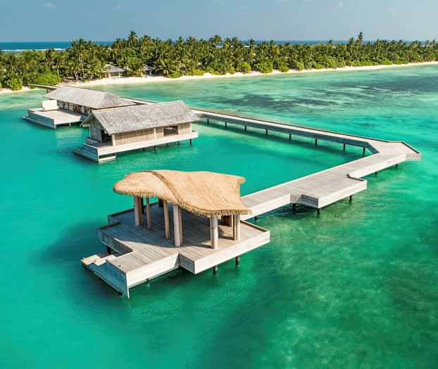 Overvannsbungalower ved en tropisk strand med turkis hav. (AI-generert tekst)