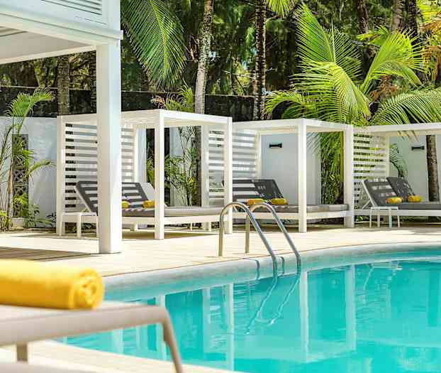 Blått basseng med hvite solsenger og grønne palmer i bakgrunnen. (AI-generert tekst)