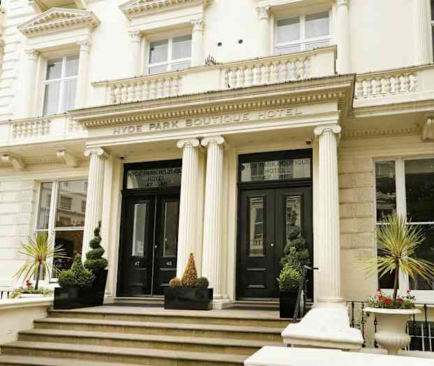 Fasaden til et boutiquehotell med hovedinngang og søyler. (AI-generert tekst)