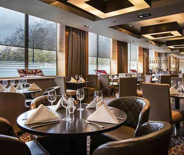 En elegant restaurant med dekkede bord med hvite servietter og vinglass. (AI-generert tekst)