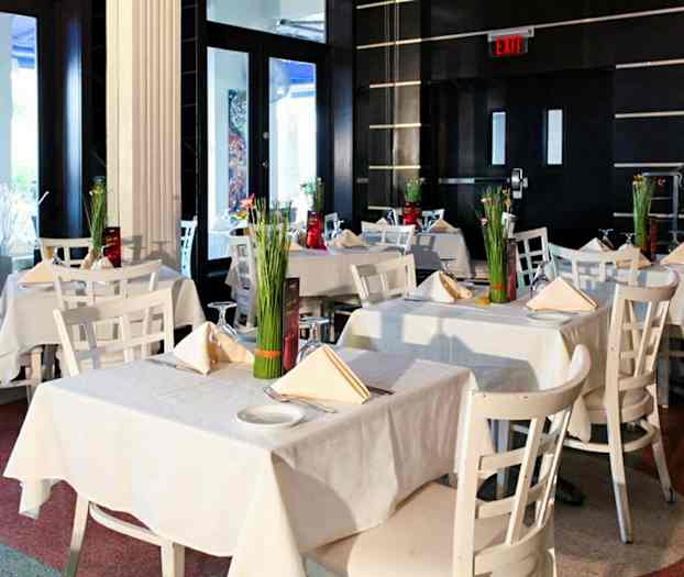 Et elegant restaurantområde med hvite bord og stoler dekorert med blomster. (AI-generert tekst)