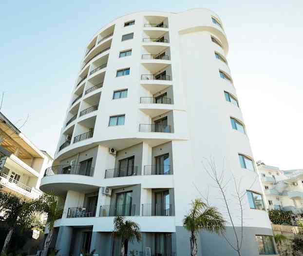 Høyhus med hvit fasade og balkonger. (AI-generert tekst)