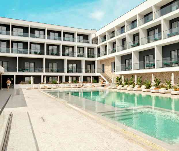 Hotellbygning med basseng og solsenger i forgrunnen. (AI-generert tekst)