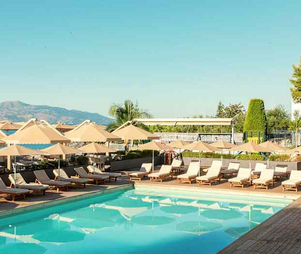 Et utendørs svømmebasseng omgitt av solsenger og parasoller. (AI-generert tekst)