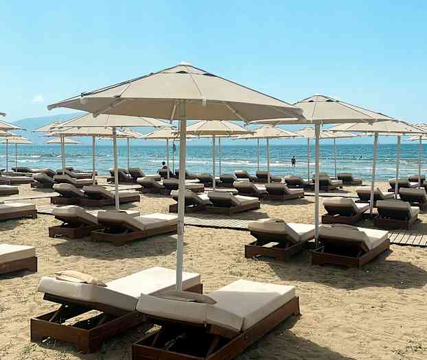 Solstoler og parasoller på en strand med havutsikt. (AI-generert tekst)