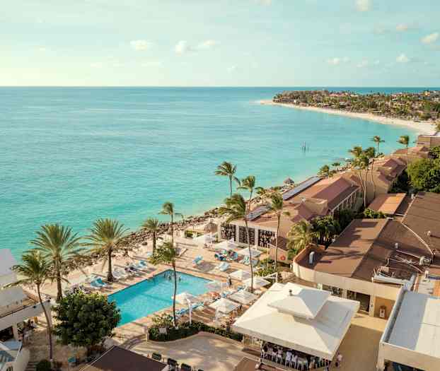 Utsikt over kystområde med turkis hav og resort med basseng og palmer. (AI-generert tekst)