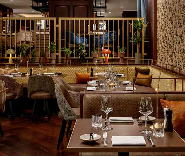 En moderne restaurant med dekkede bord, sofaer og stoler, dekorert med planter og komfortable detaljer. (AI-generert tekst)