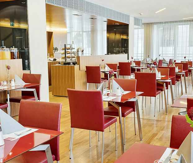 En restaurant med røde stoler og dekkede bord. (AI-generert tekst)