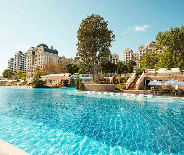 Stor utendørs basseng foran et hotell med klassisk arkitektur. (AI-generert tekst)