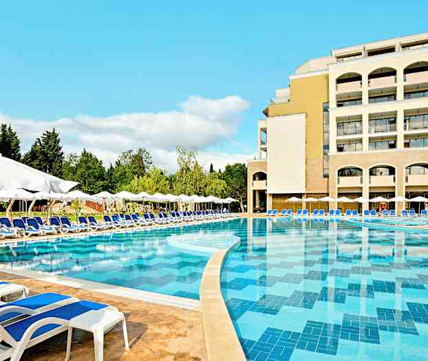 Et stort basseng med blått vann omgitt av solsenger og parasoller, med et hotell i bakgrunnen. (AI-generert tekst)