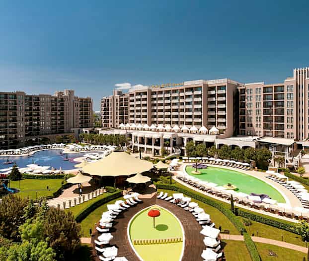 Hotellområde med store bygninger, bassenger og grønne områder. (AI-generert tekst)