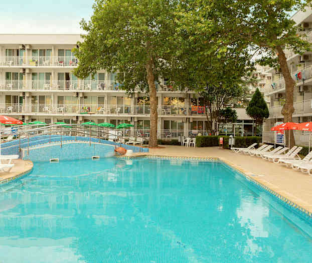 Et utendørsbasseng med solstoler og parasoller foran en bygning med balkonger. (AI-generert tekst)