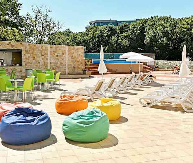 Solstoler og parasoller ved et basseng, med fargerike sittepuffer og grønne stoler. (AI-generert tekst)