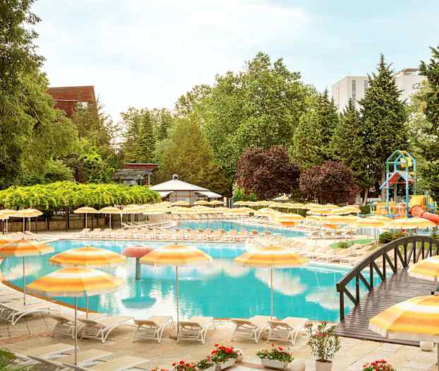 Bassengområde med solsenger og gule parasoller, omgitt av frodig vegetasjon. (AI-generert tekst)