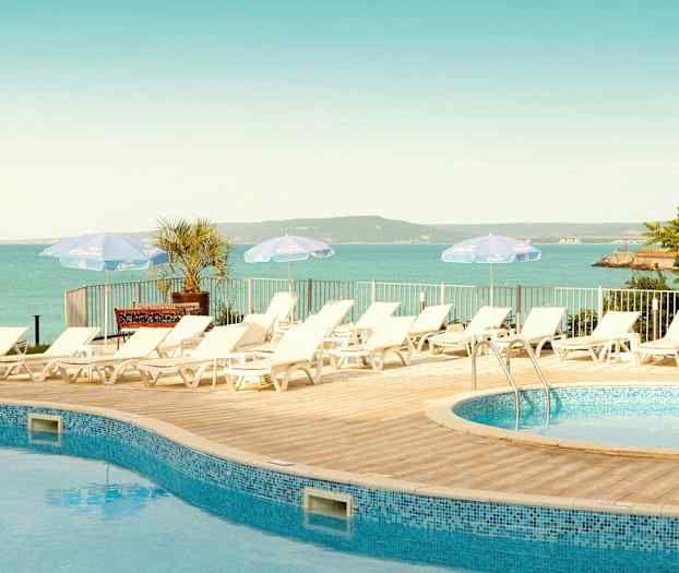 Solstoler ved et basseng med utsikt over havet og landskapet. (AI-generert tekst)