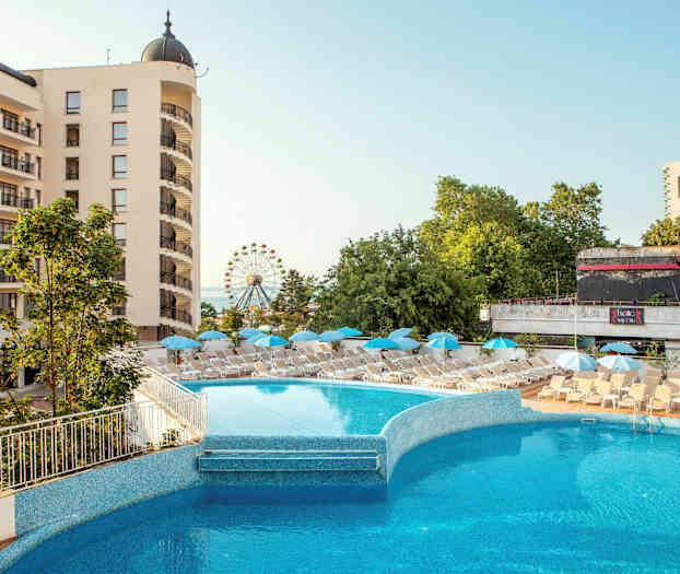 Hotellbygning med balkonger, et utendørsbasseng og solsenger med parasoller. Bakgrunnen viser grønne trær og et pariserhjul. (AI-generert tekst)