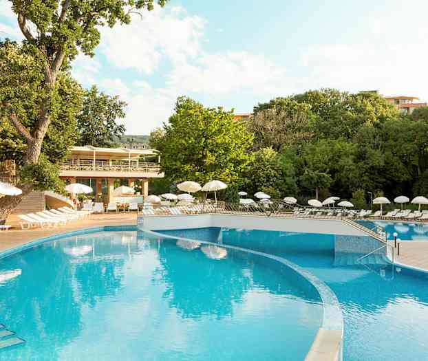 Utendørs svømmebasseng omgitt av solsenger og parasoller, omgitt av grønne trær. (AI-generert tekst)